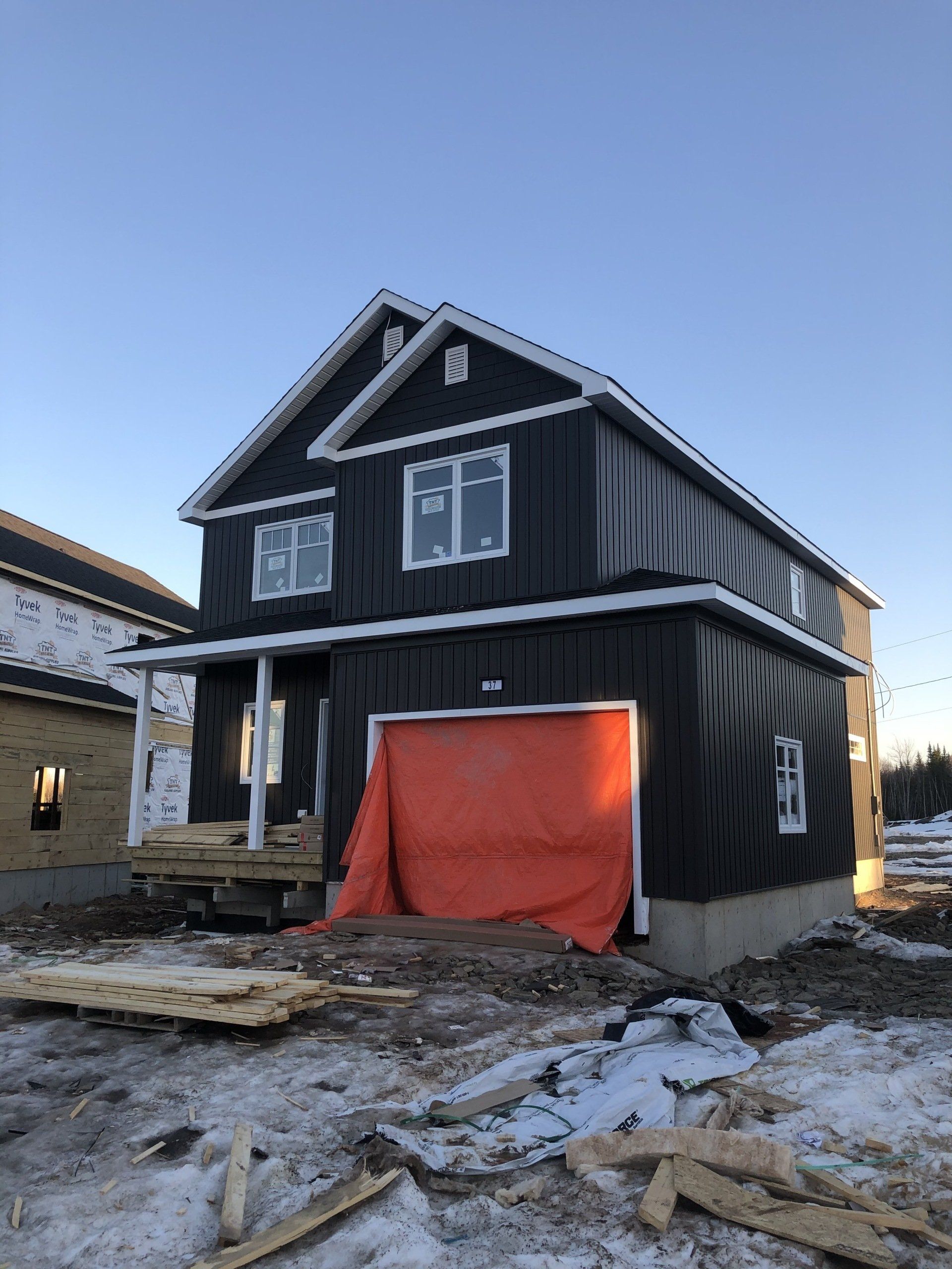 A large black house is being built in the snow.
