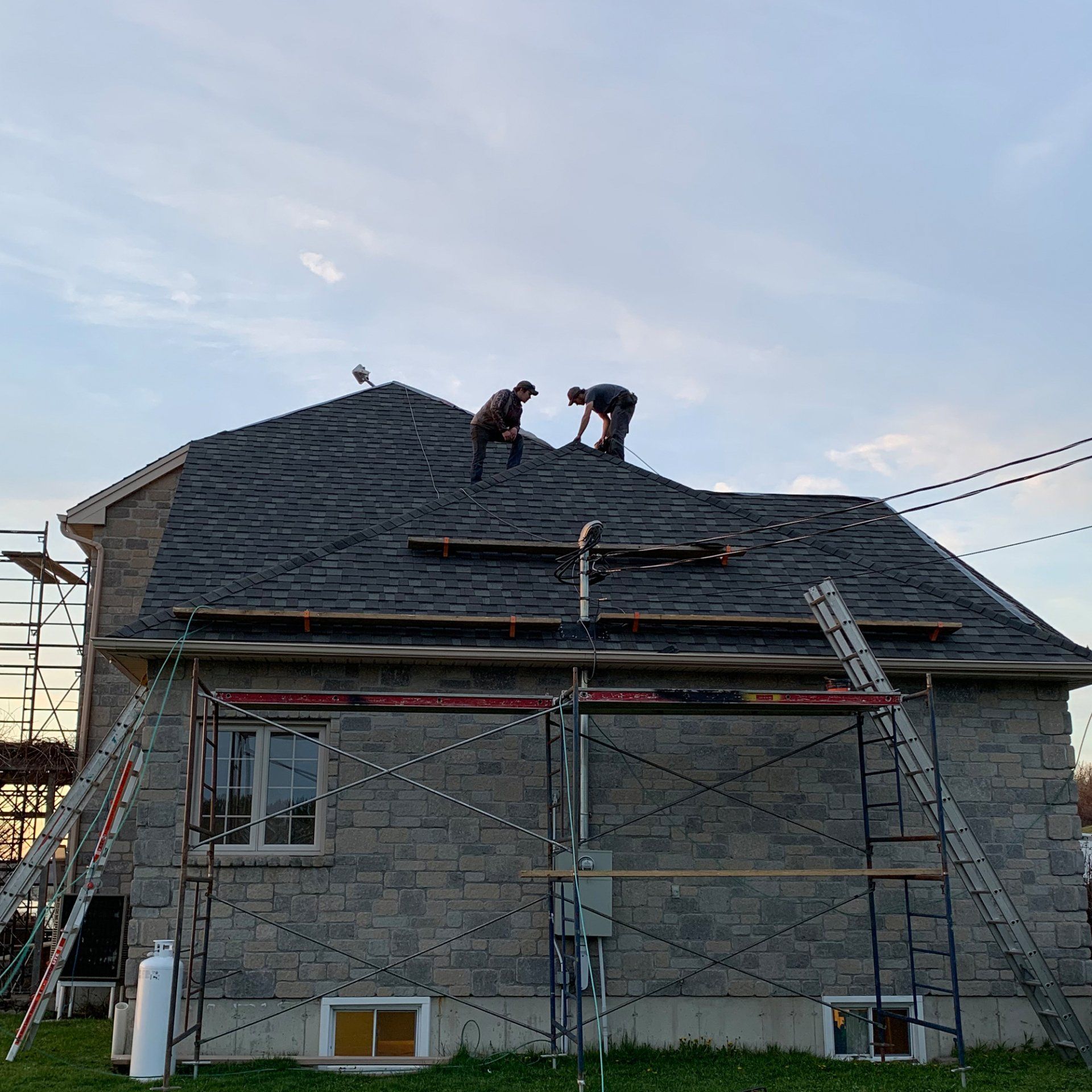 Two men are working on the roof of a house.