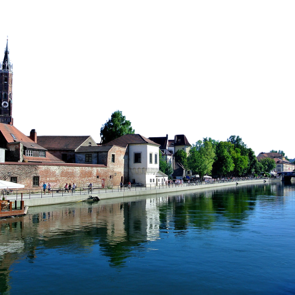Ein Fluss fließt durch eine kleine Stadt mit einem Glockenturm im Hintergrund