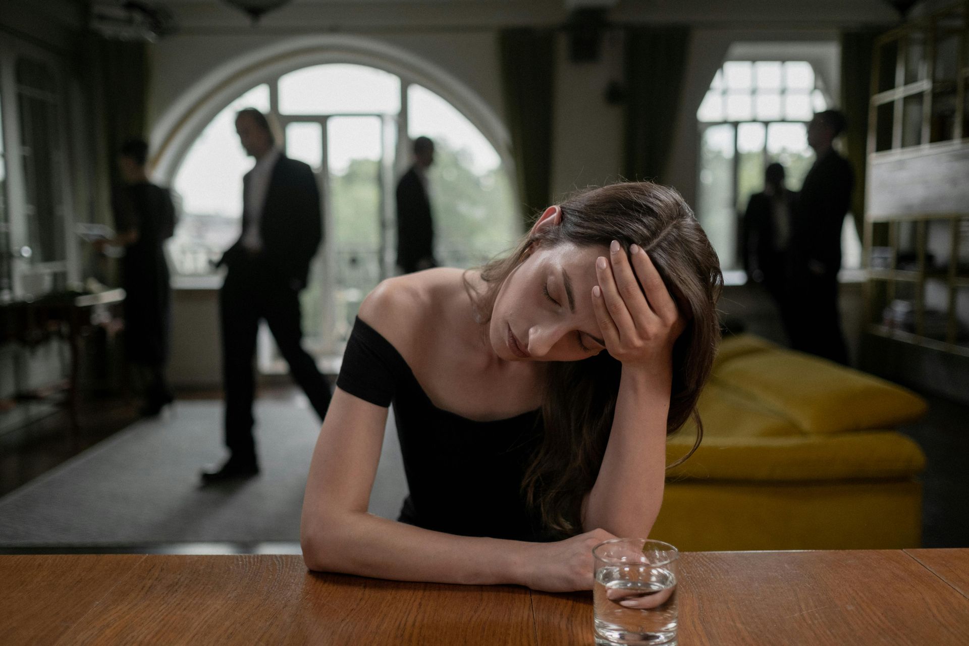 Woman in a black dress with head in hand, looking tired