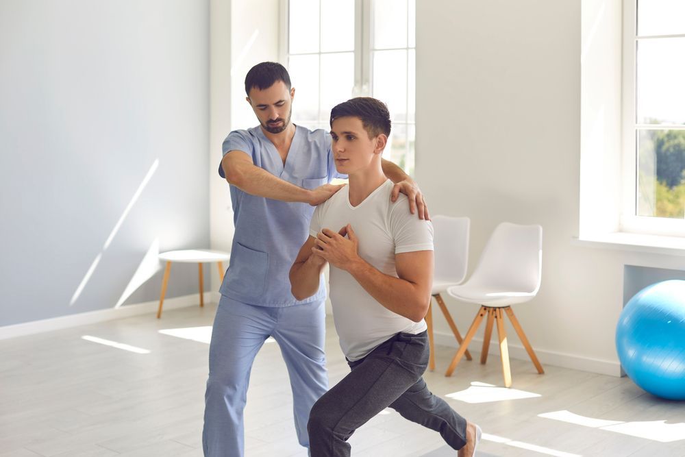 A man is being helped by a physical therapist in a room.