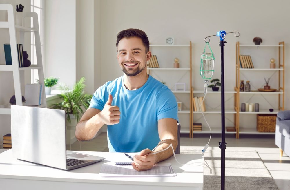 A man is sitting at a desk with a laptop and giving a thumbs up.