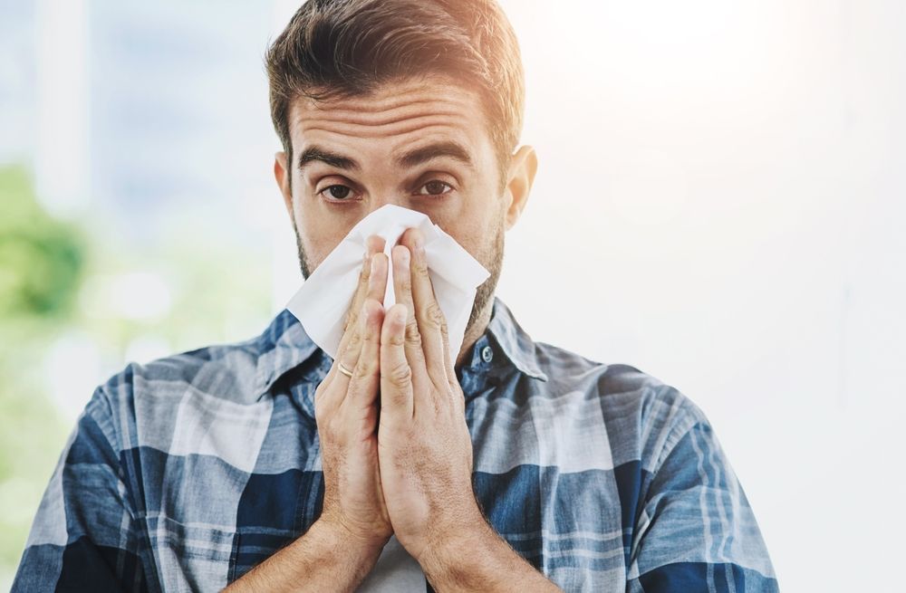 A man is blowing his nose into a napkin.