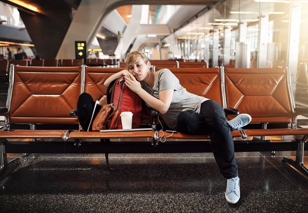 A woman is sleeping on a bench at an airport