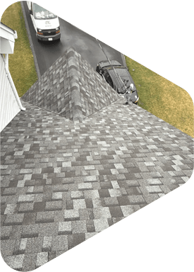 Overhead view of a gray shingle roof, with a van and car in the driveway below.