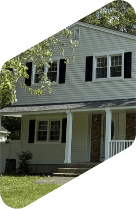 Two-story house with light siding, black shutters, and a covered porch.