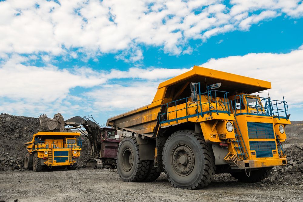 Two Yellow Dump Trucks Are Parked Next to Each Other in a Dirt Field — Wilsons Plant In Bellambi, NSW