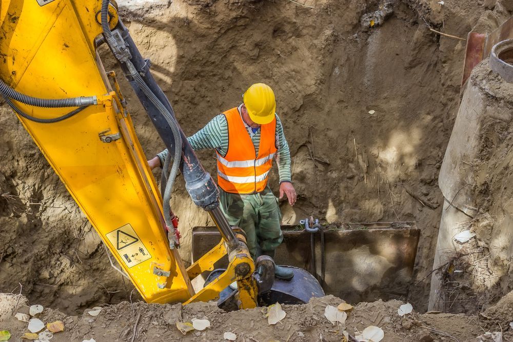 A Construction Worker is Digging a Hole With a Yellow Excavator — Wilsons Plant In Bellambi, NSW