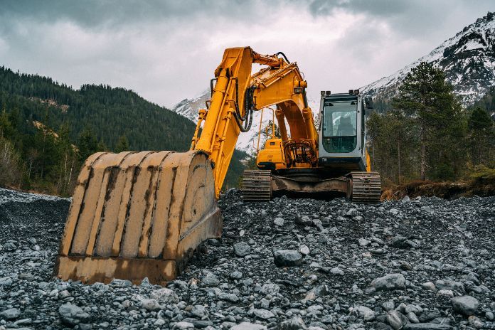 A Yellow Excavator is Working on a Rocky Hillside in the Mountains — Wilsons Plant in Wollongong, NSW