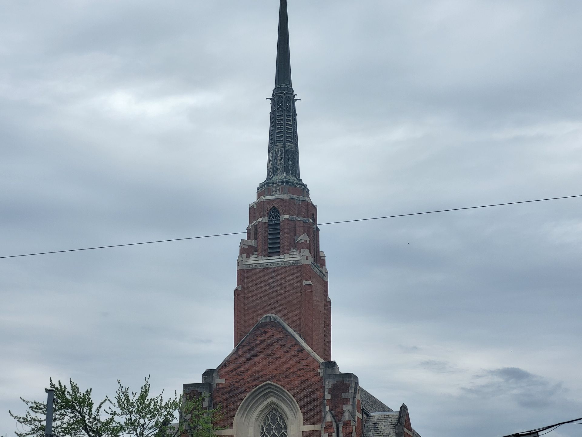 A large brick church with a steeple against a cloudy sky