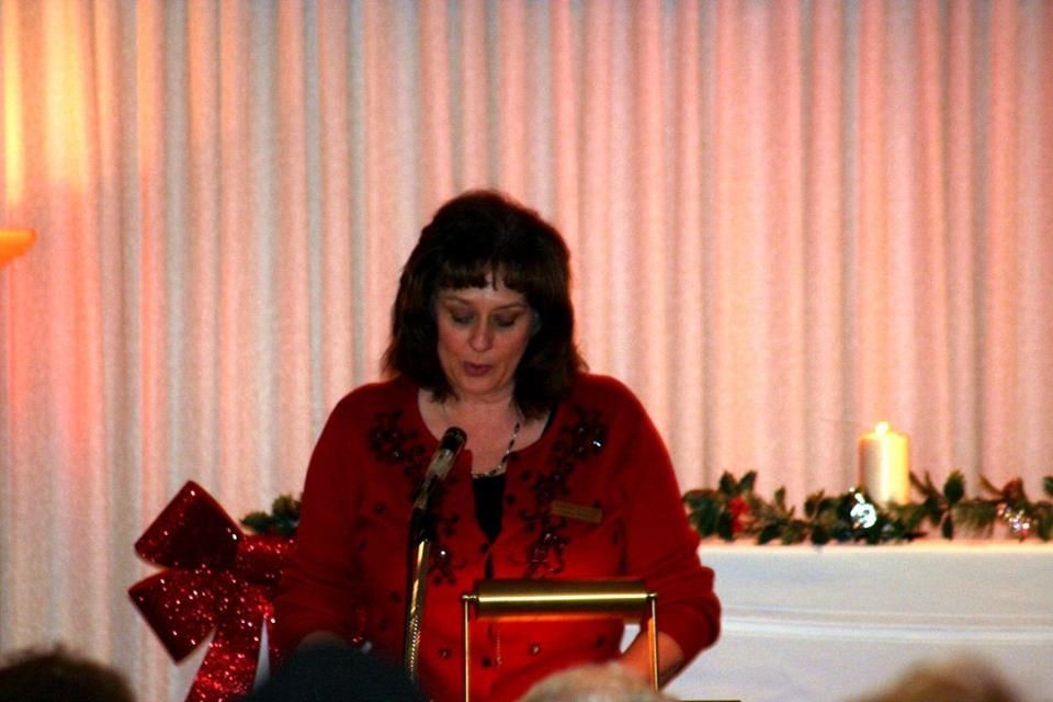 a woman in a red sweater is standing at a podium giving a speech .