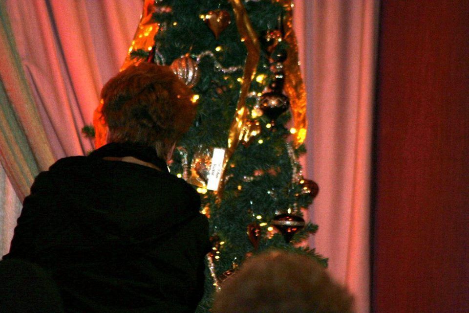 a woman is decorating a christmas tree in a dark room .