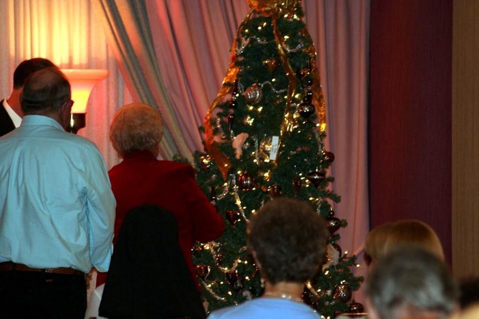 a group of people standing in front of a christmas tree