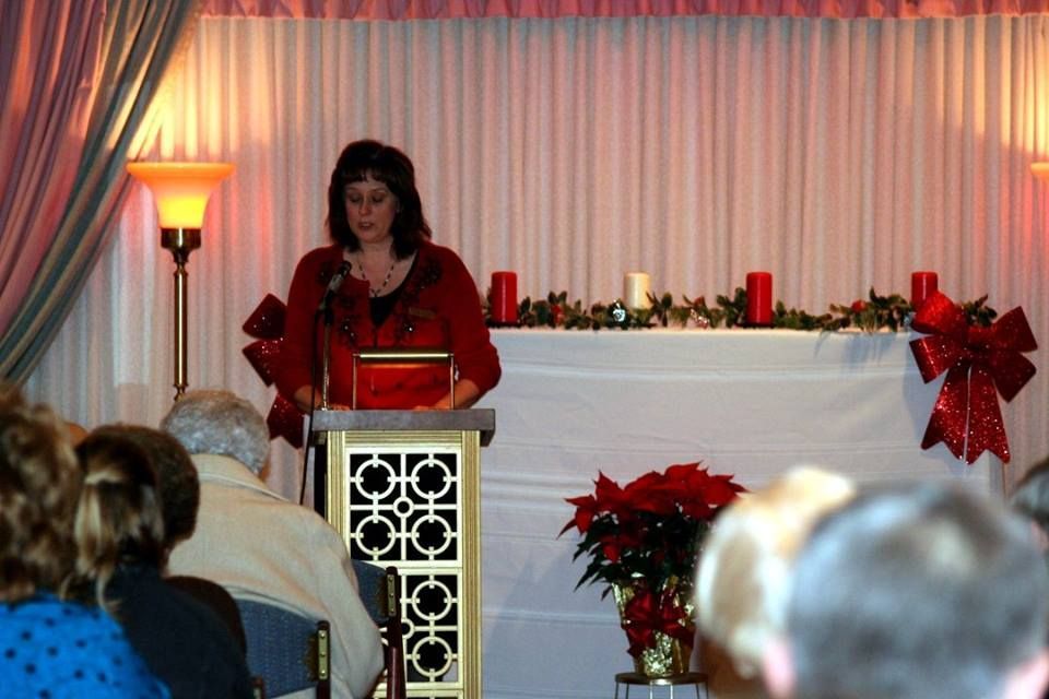 a woman is giving a speech at a podium in front of a crowd