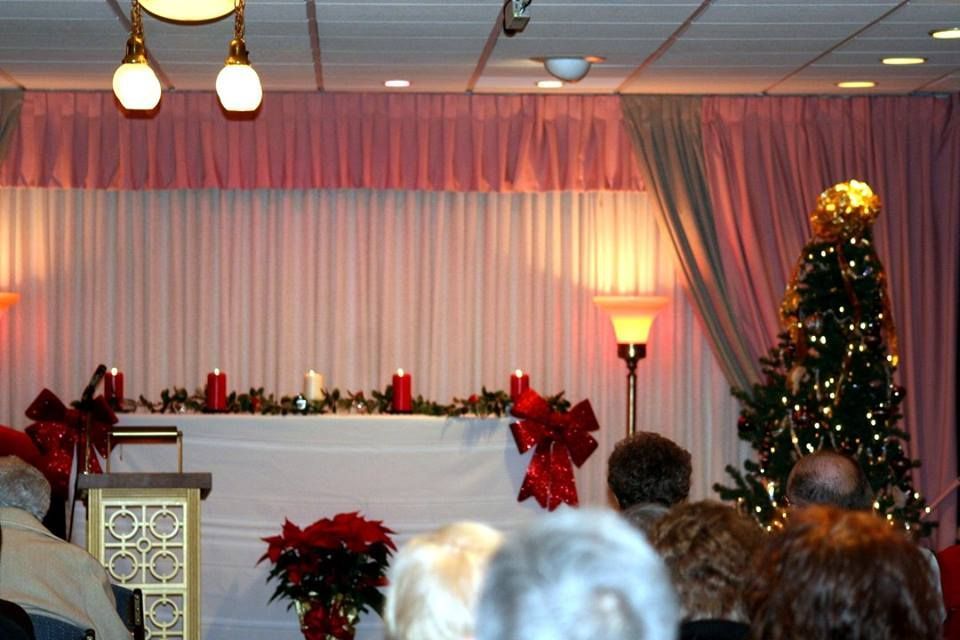 a group of people sitting in front of a stage with a christmas tree in the background