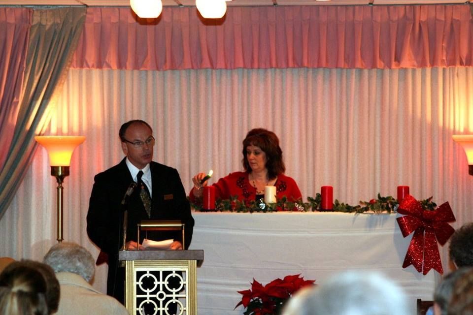 a man stands at a podium while a woman holds a candle
