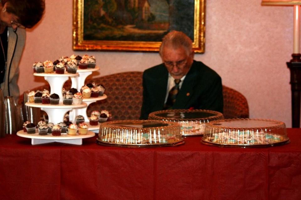 a man sits at a table with cupcakes on it