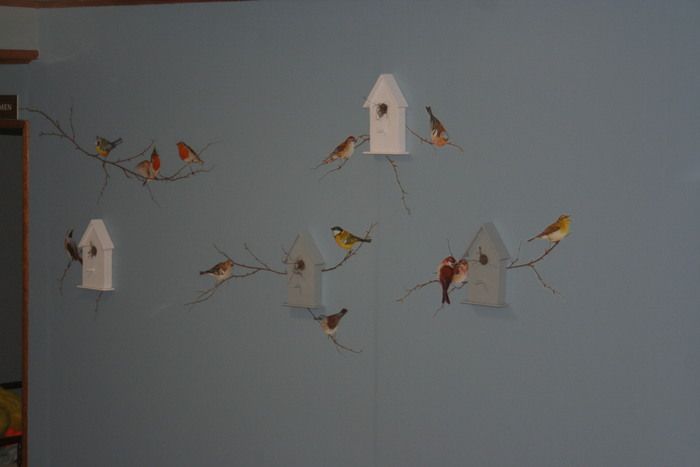 a blue wall with birds and birdhouses on it