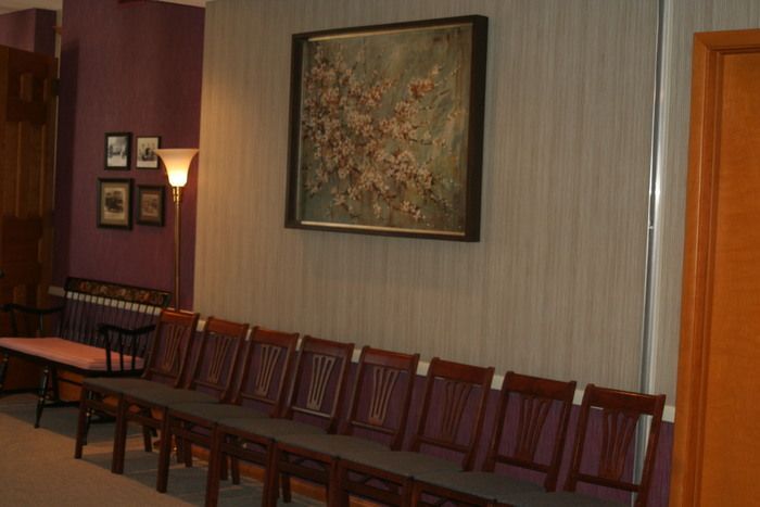 a row of chairs in a waiting room with a painting on the wall above them