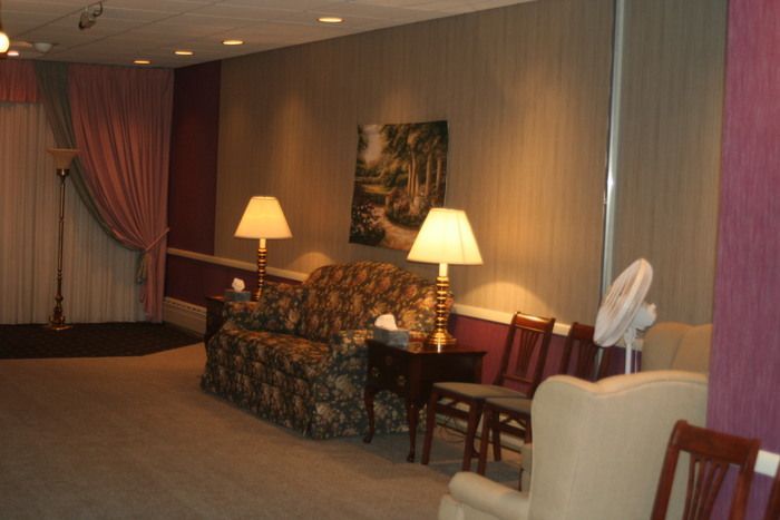 a living room with a couch , chairs , lamps and a fan