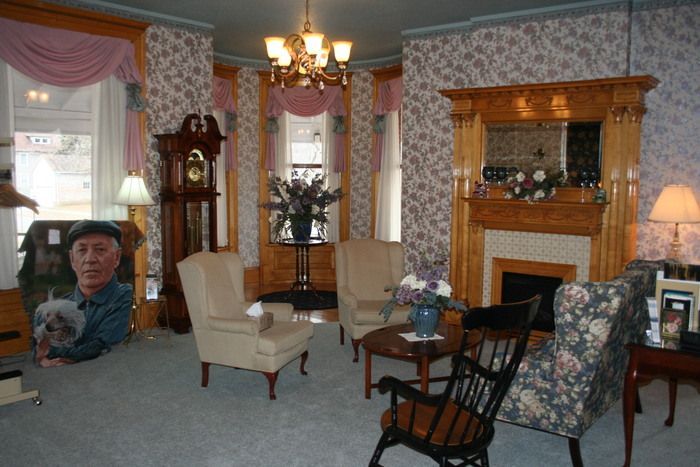 a living room with chairs a clock and a fireplace