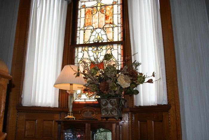 a vase of flowers sits in front of a stained glass window .