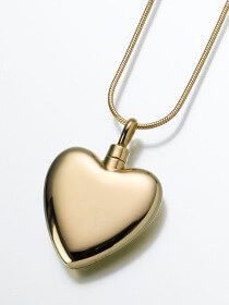 a gold heart shaped urn necklace on a chain .