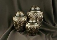 three urns are sitting on top of a black cloth on a table .