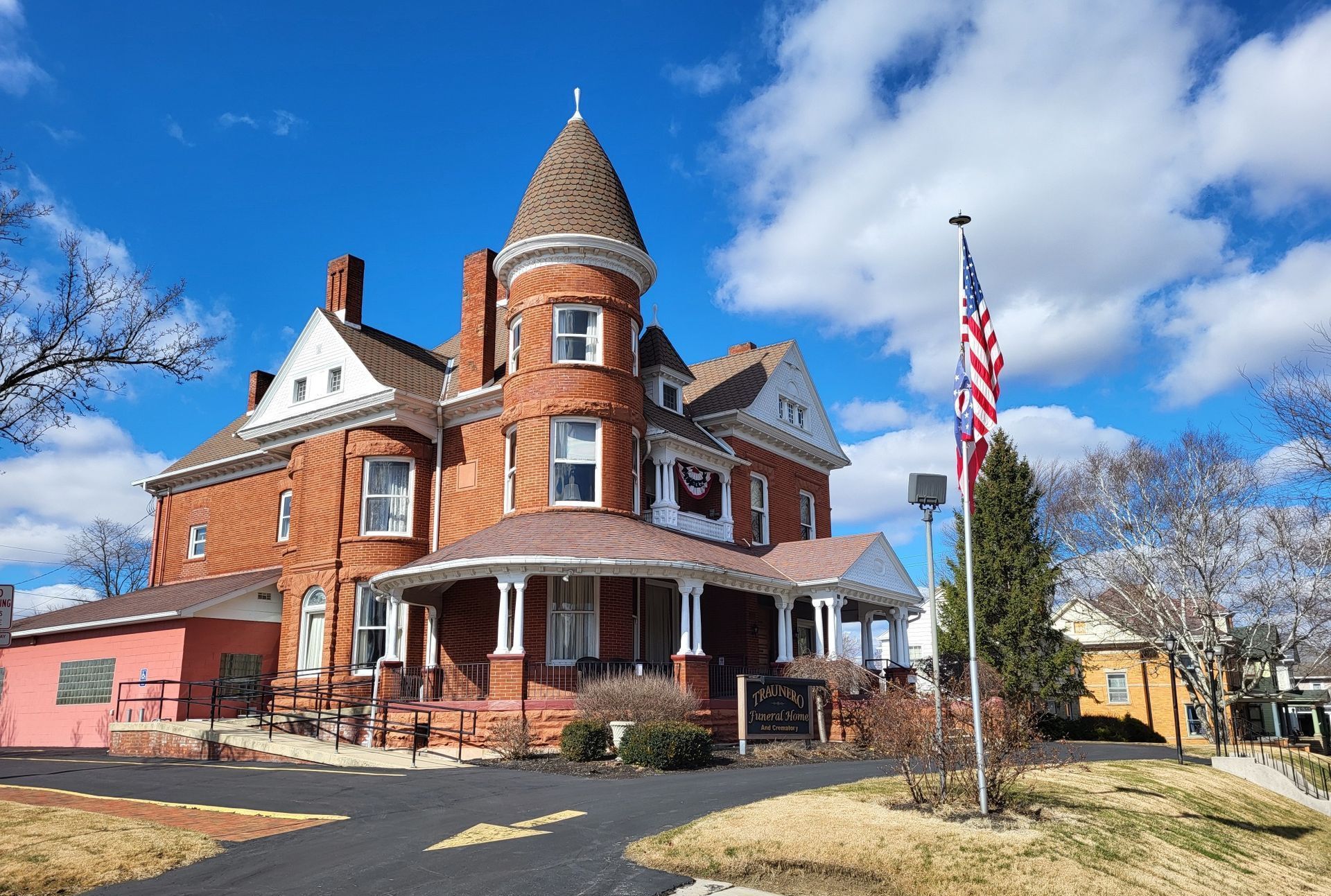 A large brick house with a tower and an american flag in front of it.