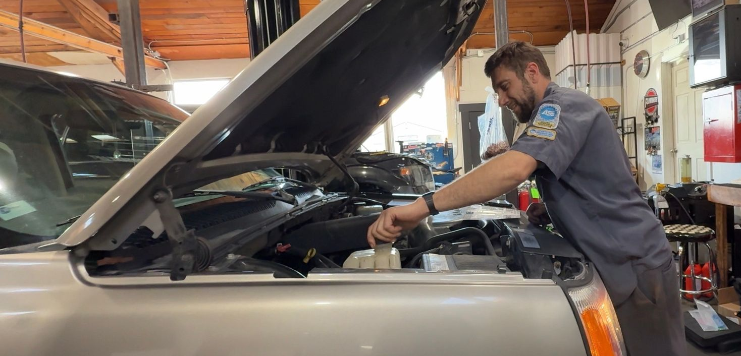 Technician inspecting vehicle cooling system and coolant reservoir at Wayside Garage in Seaside CA