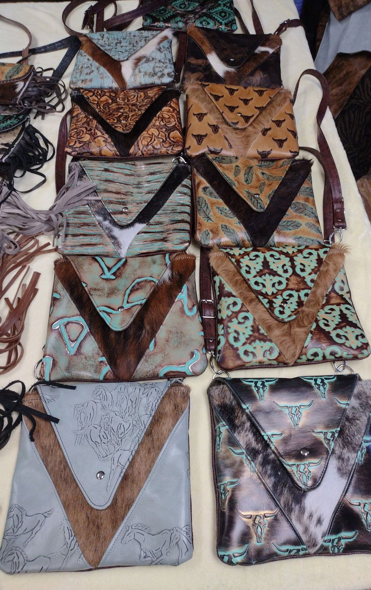 A collection of handmade leather crossbody bags, each with unique designs and textures, including turquoise, brown, and cowhide accents.