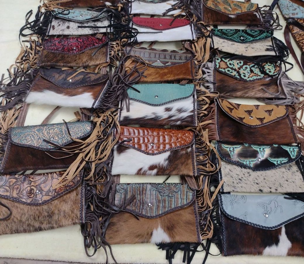 Clutch purses with cowhide patterns and fringe. Browns, tans, and some with embellishments.