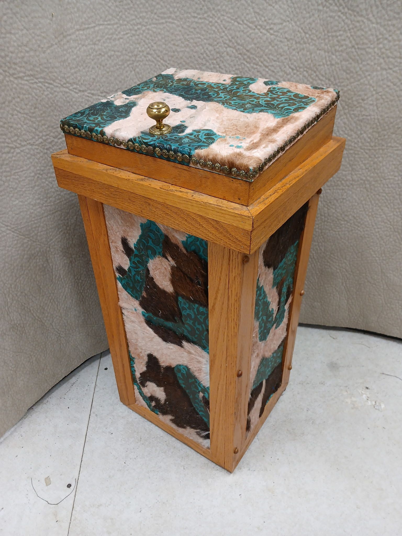 Wooden wastebasket with a camouflage fabric design on the sides and lid, gold knob on top.