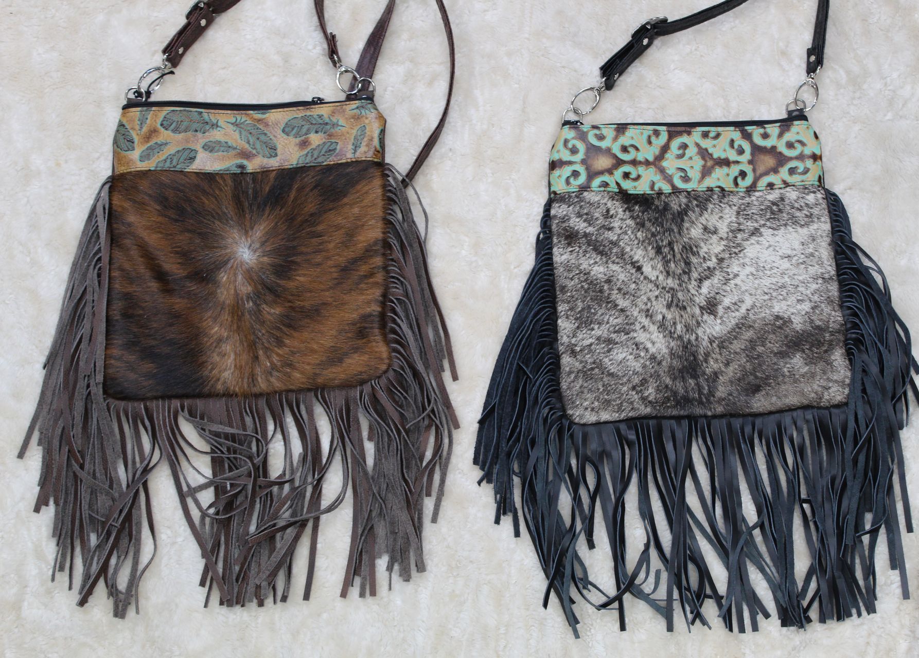 Two fringed cowhide crossbody bags, brown and black, with patterned tops and leather straps.