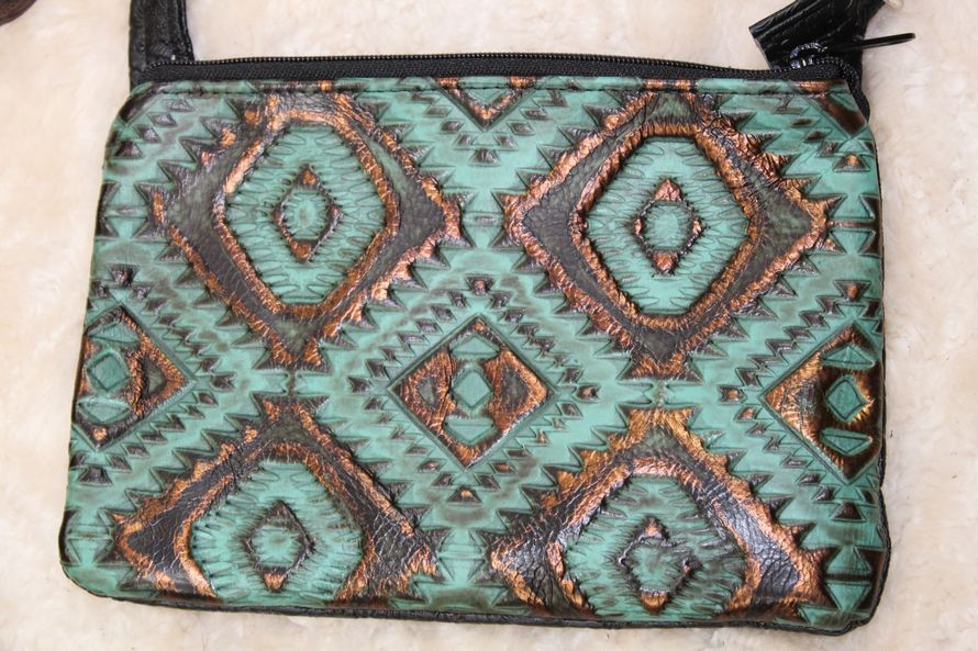 Teal crossbody bag with copper-colored geometric patterns. Features a black strap and zipper.
