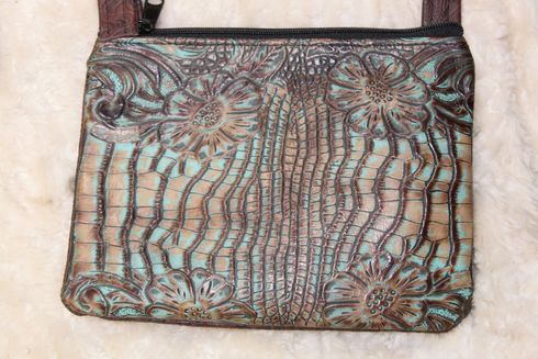 Turquoise and brown leather crossbody bag with floral and vertical line embossed design.