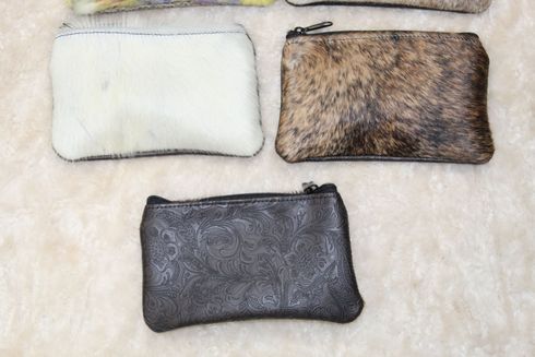 Three small zippered pouches. One is white, one is brown and furry, and one is dark gray with a textured pattern.