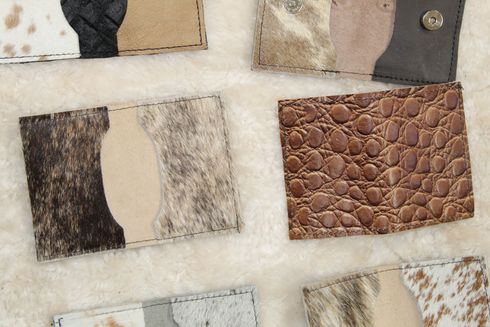 Close-up of several small, leather cardholders in various textures and patterns, including cowhide and alligator print.