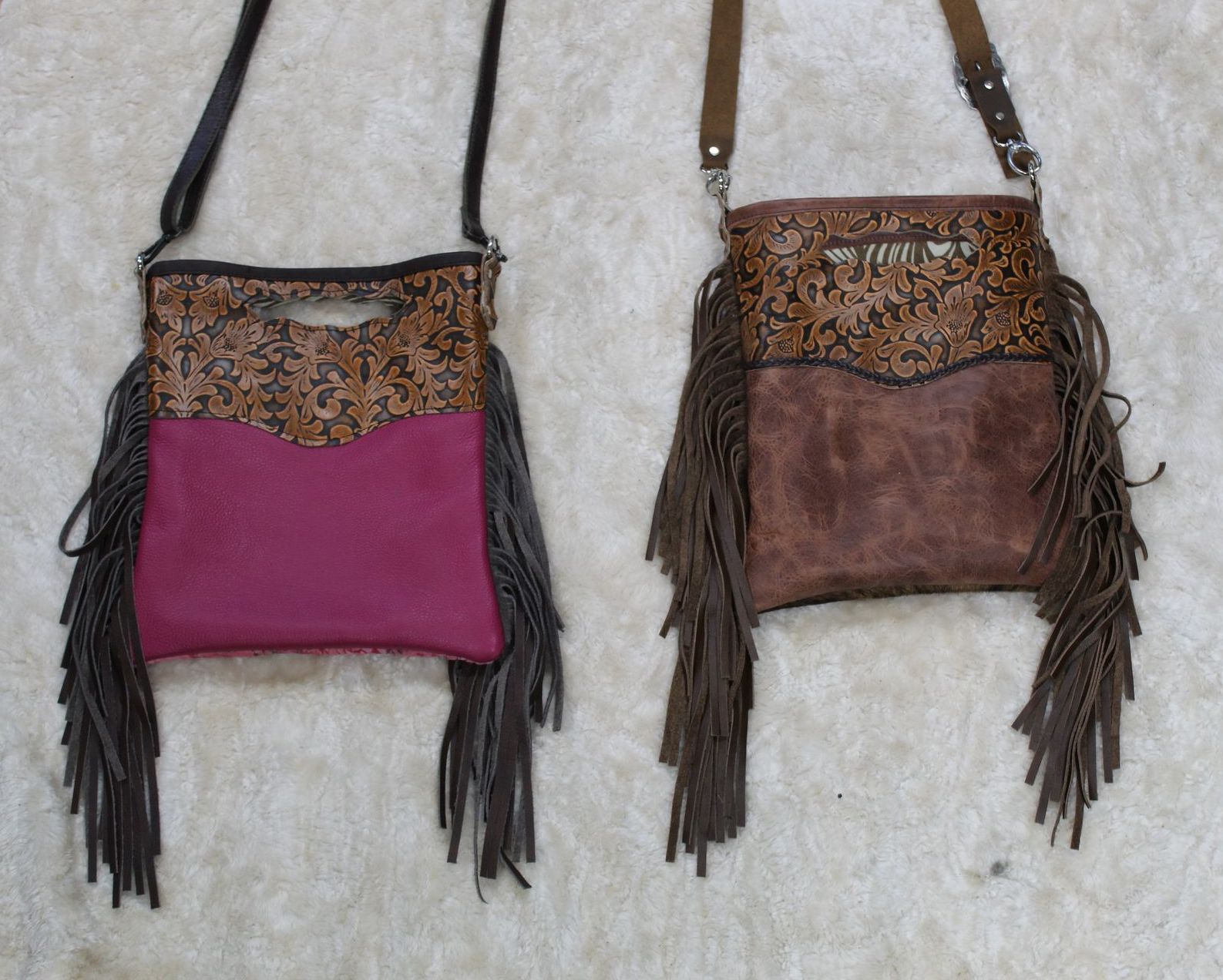 Two leather crossbody bags with fringe, one purple, one brown, on a textured surface.