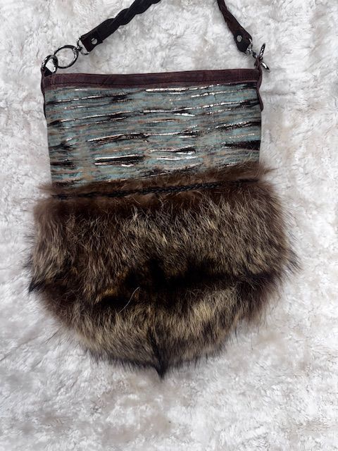 Brown and blue fur purse with a suede handle and a fluffy bottom, on a white background.