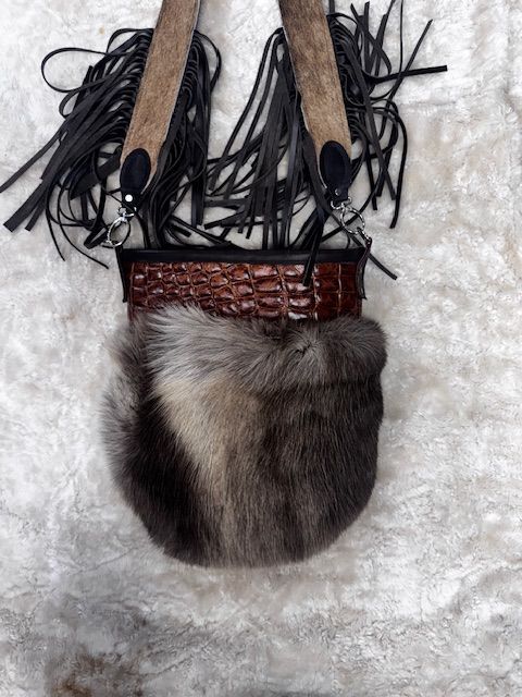 Fur pouch with leather straps, brown and grey fur, fringe detail.