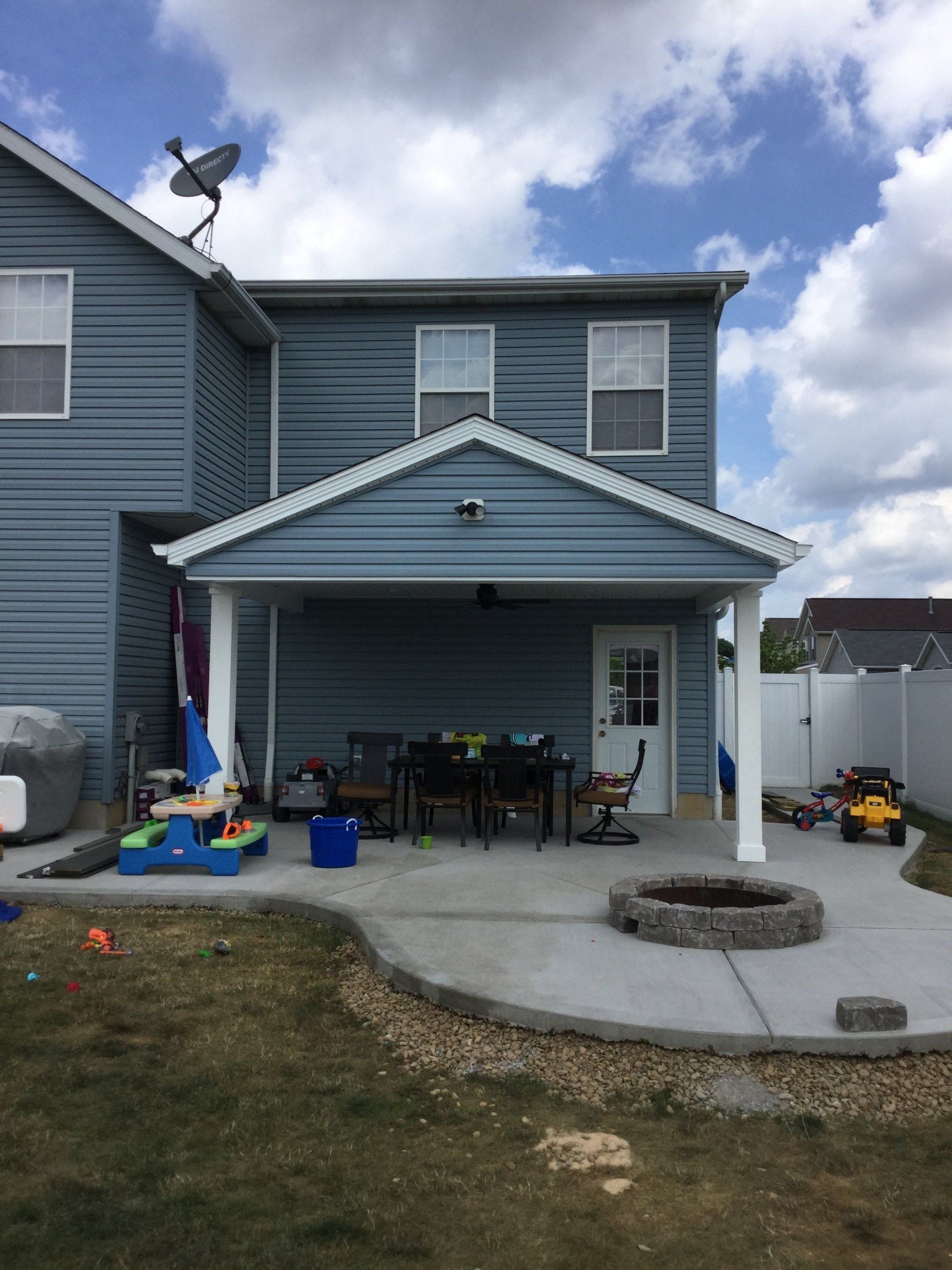 A blue house with a covered patio and a fire pit