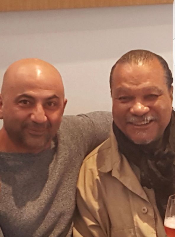 Two men posing for a picture with one holding a glass of beer