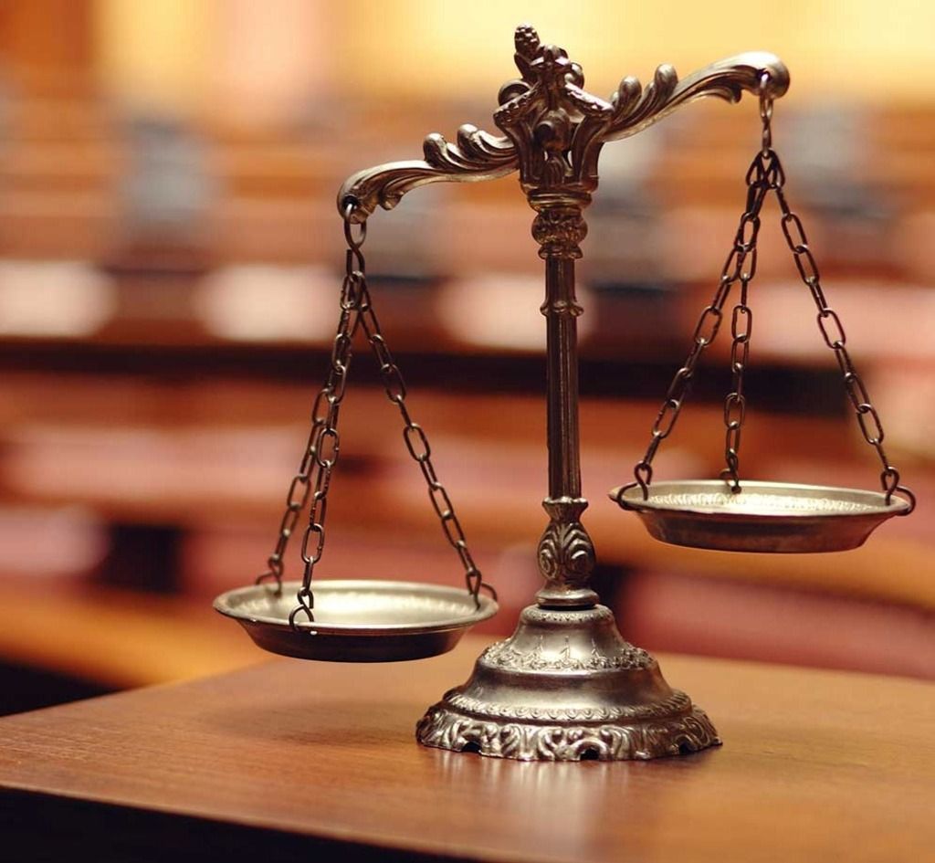 A scale of justice sits on a wooden table