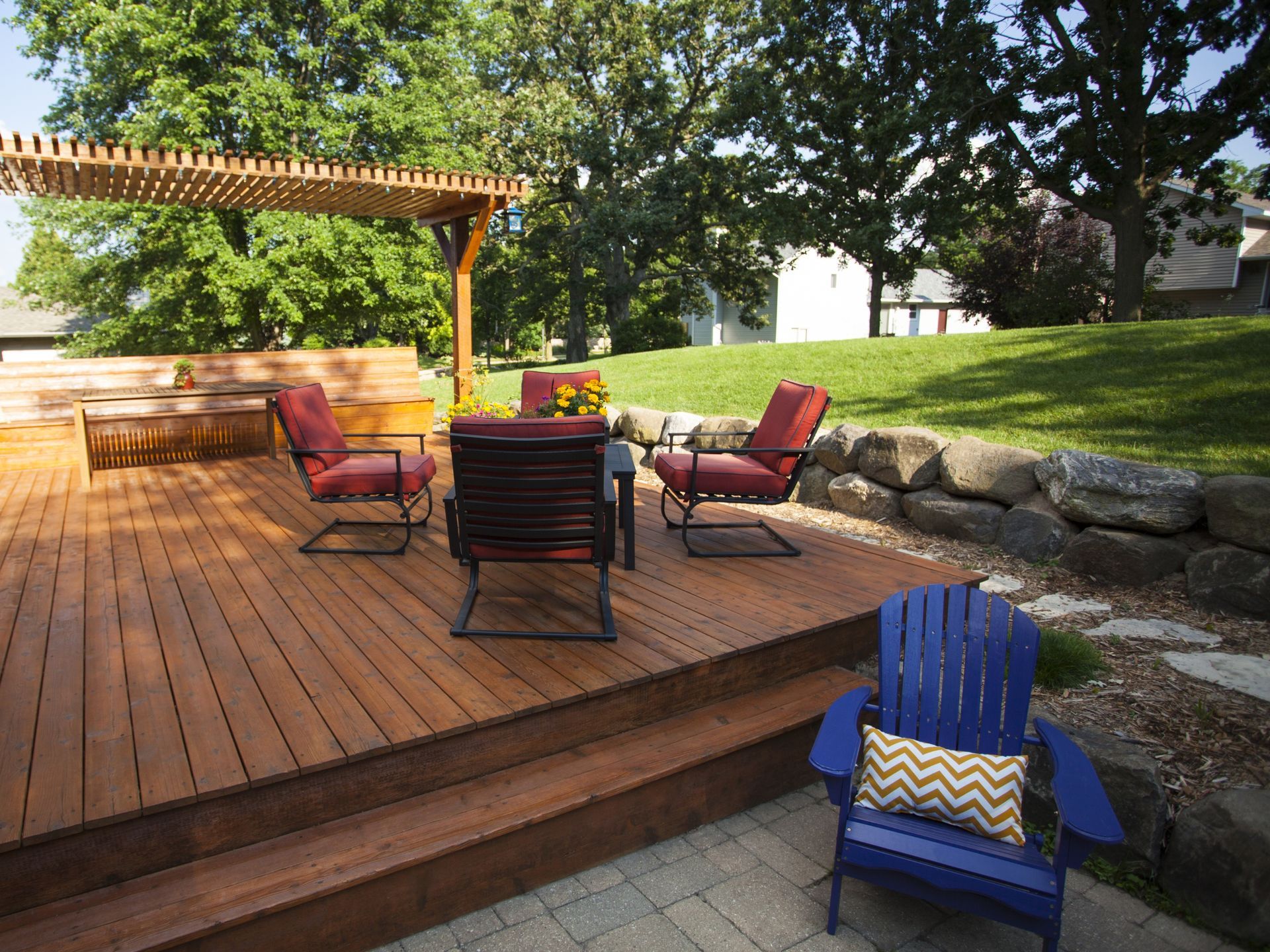 Wooden deck with seating area, pergola, and blue Adirondack chair.