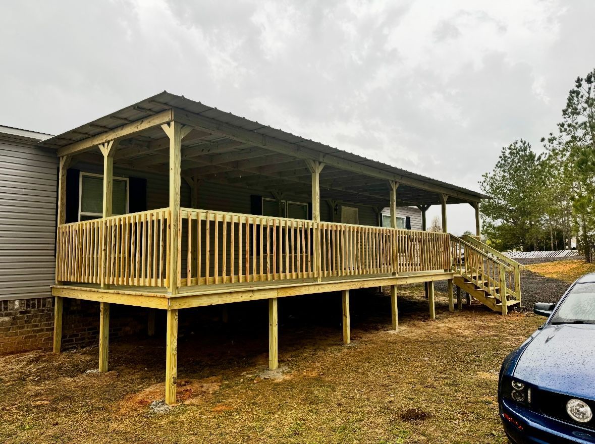 Wooden deck with a metal roof on a house, steps leading to the ground, blue car parked on the right.