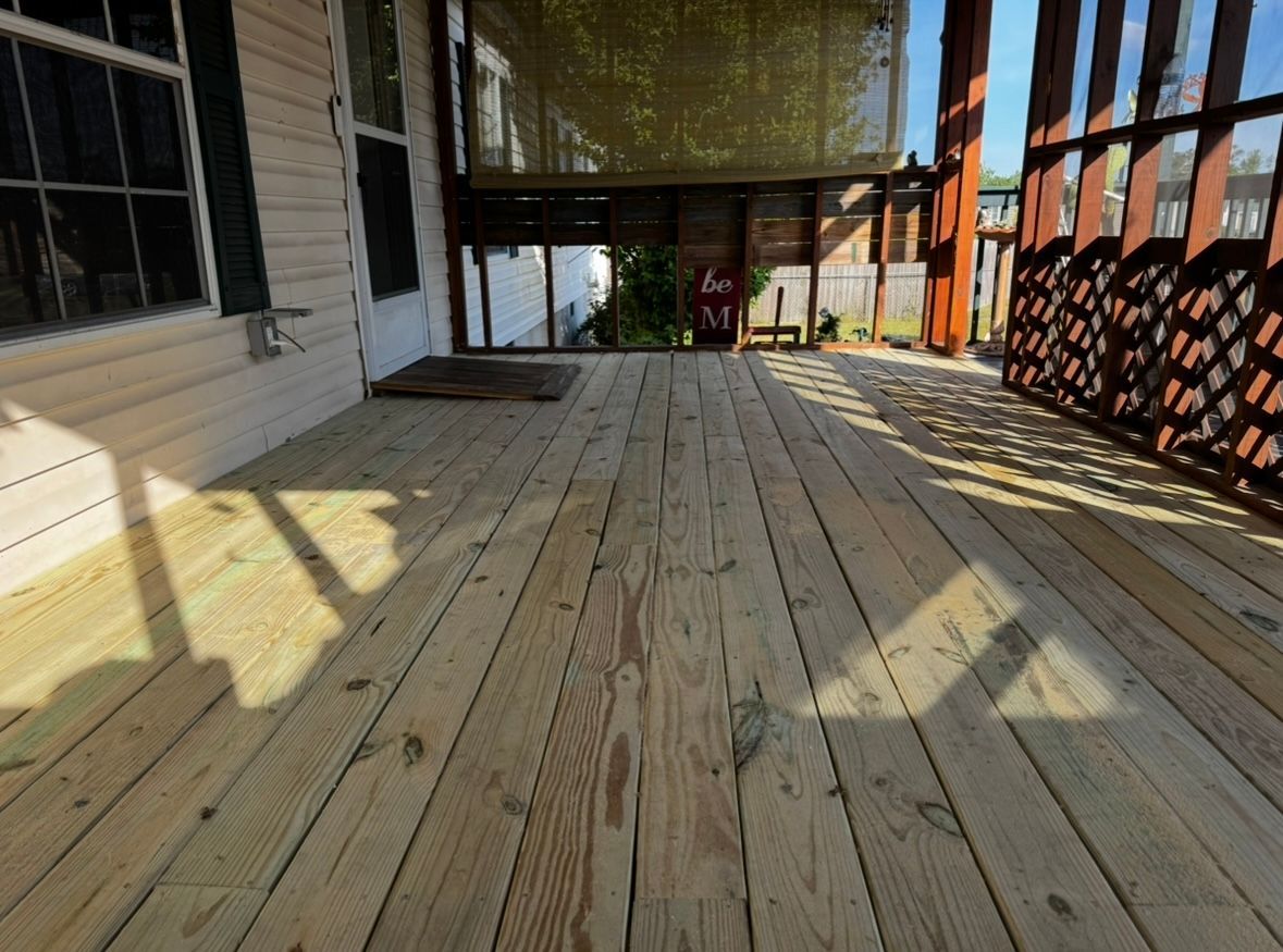 Wooden deck extending from a house, with sunlight casting shadows and latticework railing.