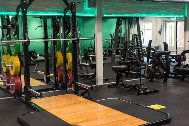 Een sportschool vol met veel fitnessapparatuur en een houten platform.