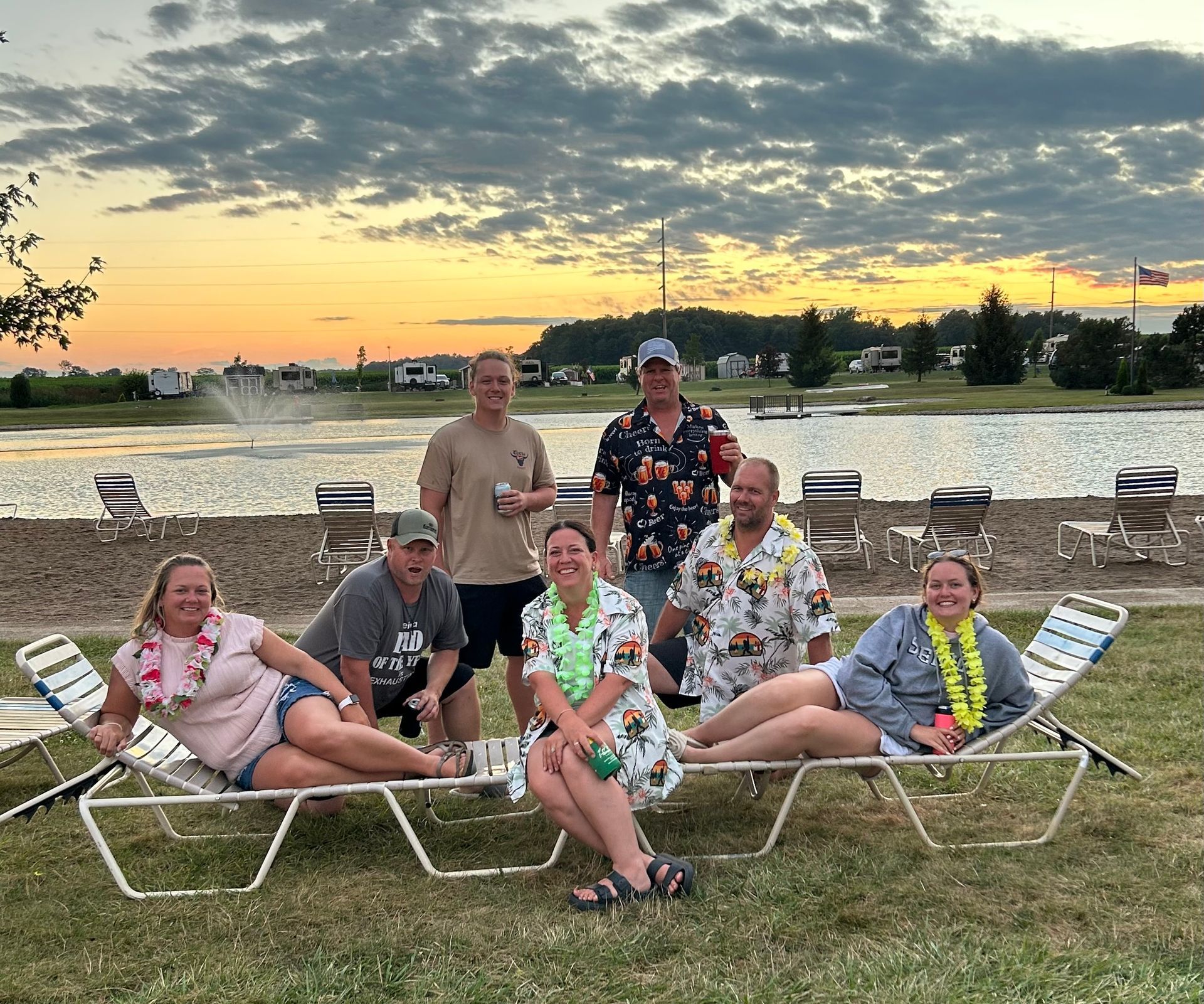 A group of people are sitting on lounge chairs in front of a lake. | Chickasaw Garage