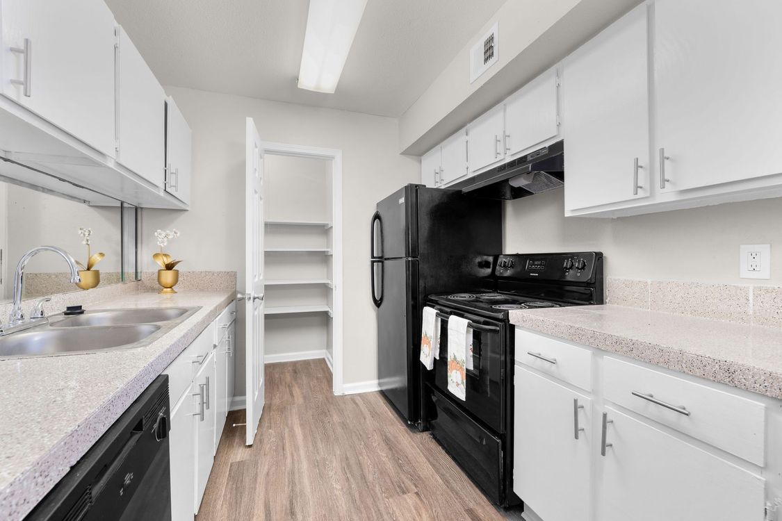 A kitchen with white cabinets and a black refrigerator at Serena Apartment Homes.